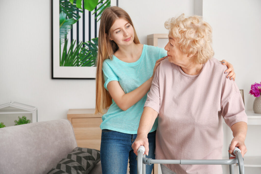 Young woman and her elderly grandmother with walking frame at home